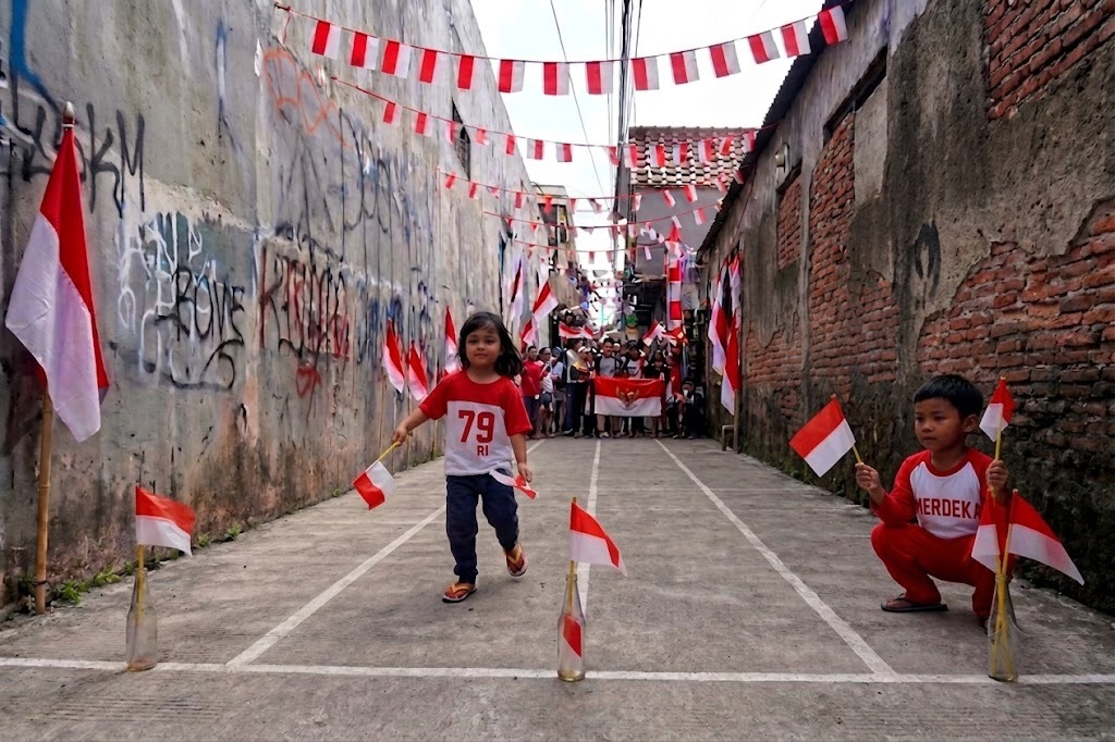 A child participates in a Red and White flag transfer challenge during Indonesia's Independence Day celebration.